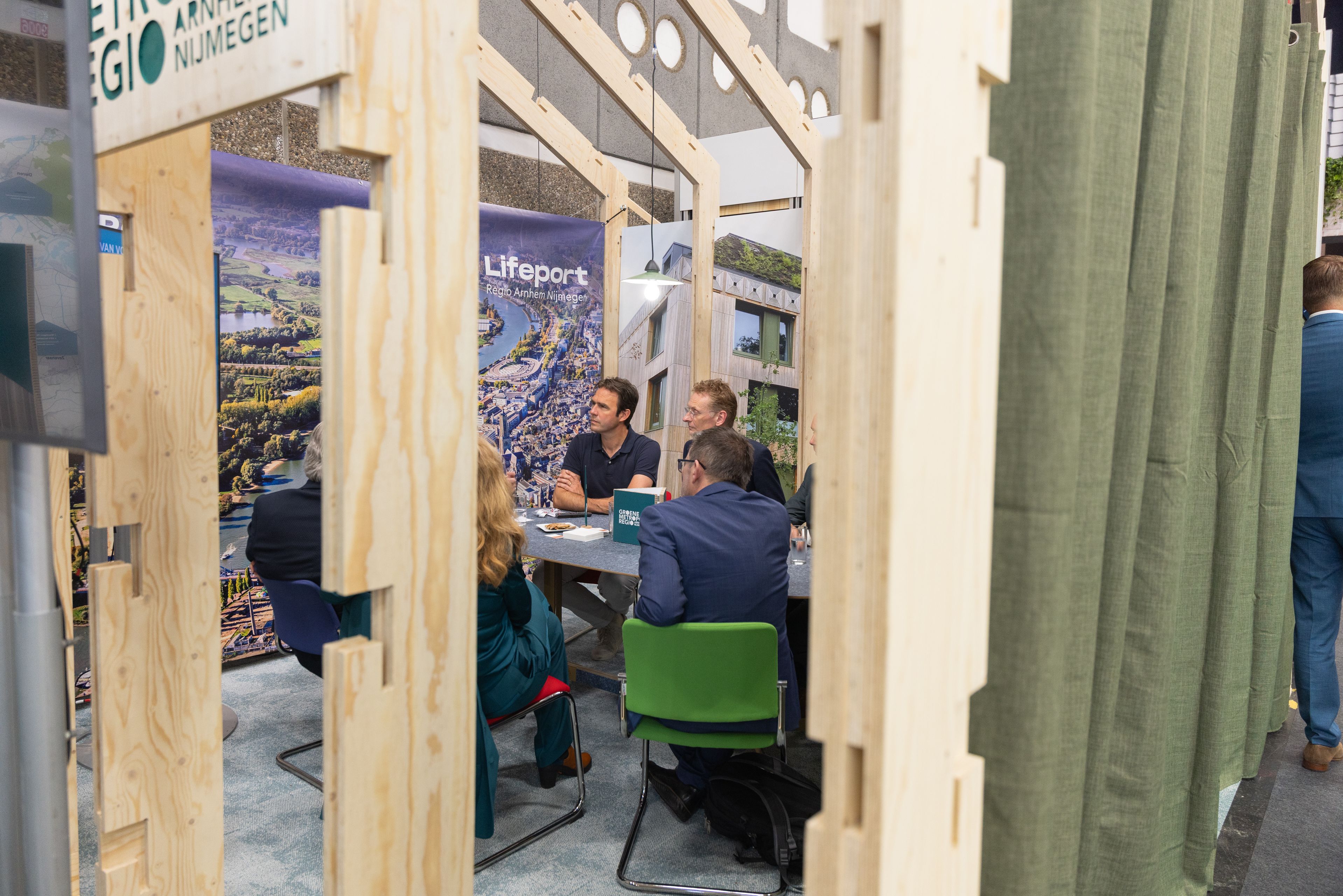 Eventfotografie Groene Metropool: Mensen in gesprek bij een stand met houten constructie en groene accenten. Joep van Drunen Photography