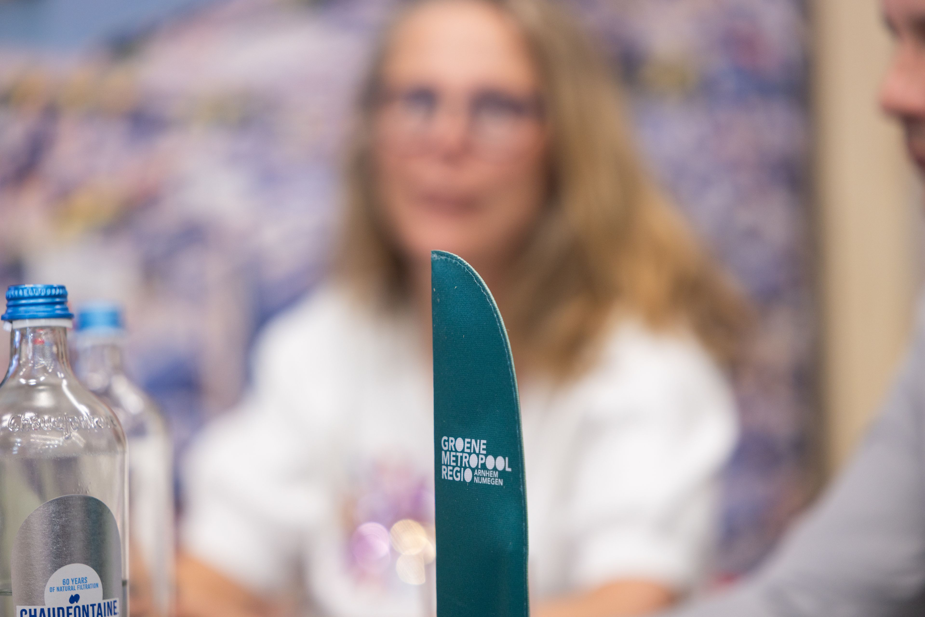 Eventfotografie Groene Metropool: Groen mes met logo Groene Metropool Regio Arnhem Nijmegen, waterflessen en personen op evenement. Joep van Drunen Photography