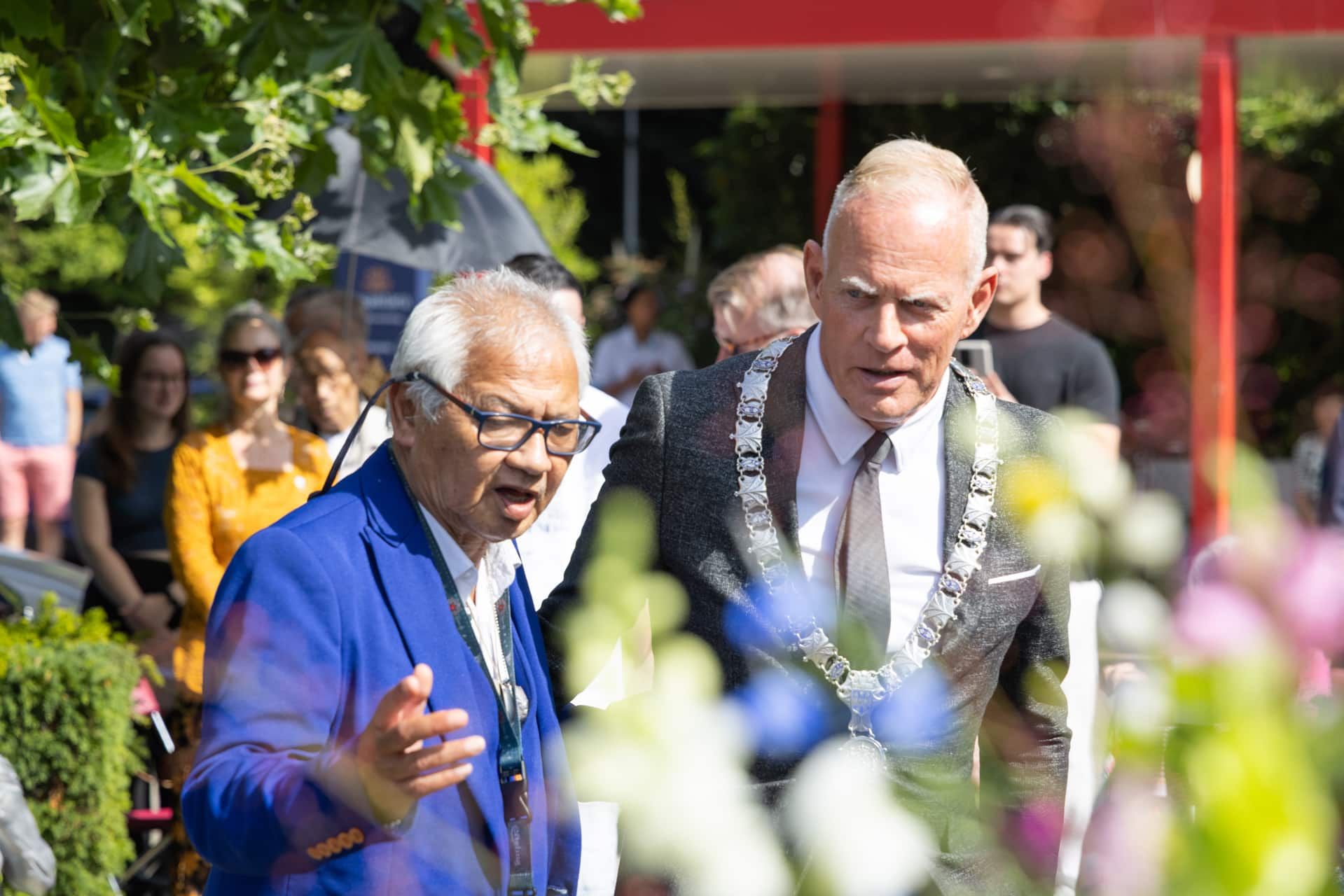 Nusantara Herdenking: Man in blauw pak spreekt met burgemeester tijdens herdenking. Joep van Drunen Photography.