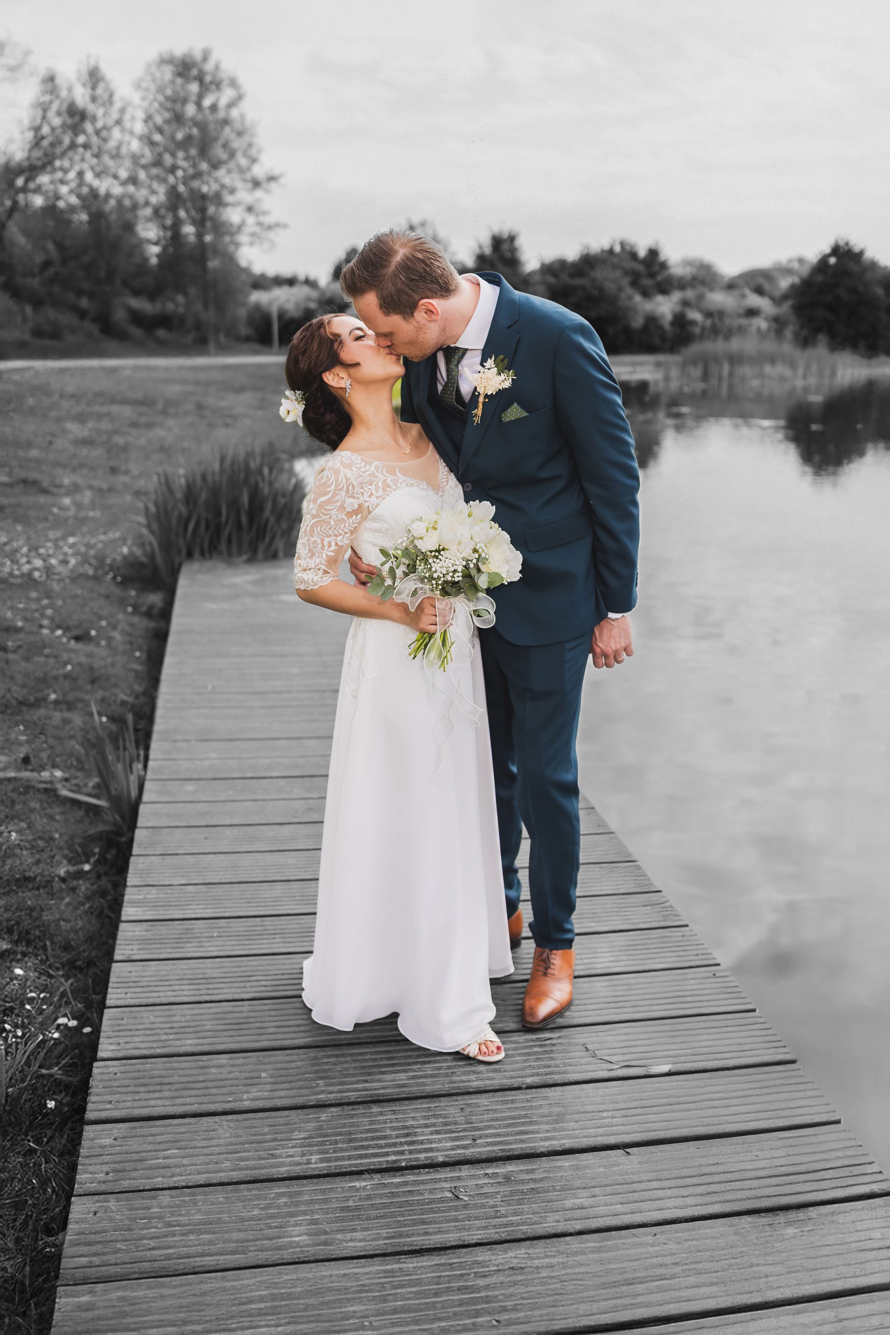 Trouwfotografie: Kussend bruidspaar op steiger aan het water. Foto door Joep van Drunen Photography, professioneel trouwfotograaf.