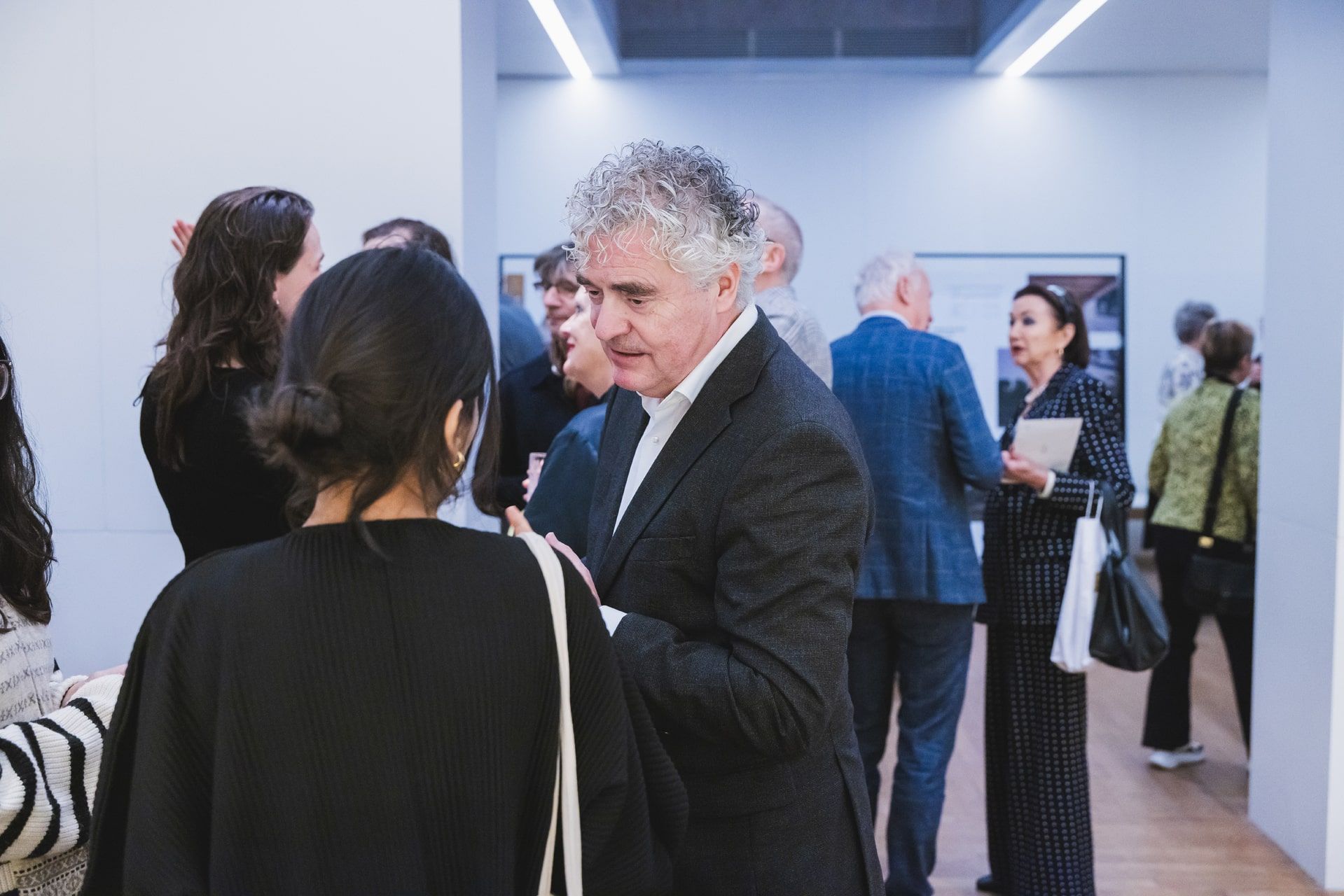 Mensen bij de Abe Bonnema Prijs uitreiking, interagerend in een lichte ruimte. JVD_9323.jpg, Joep van Drunen Photography
