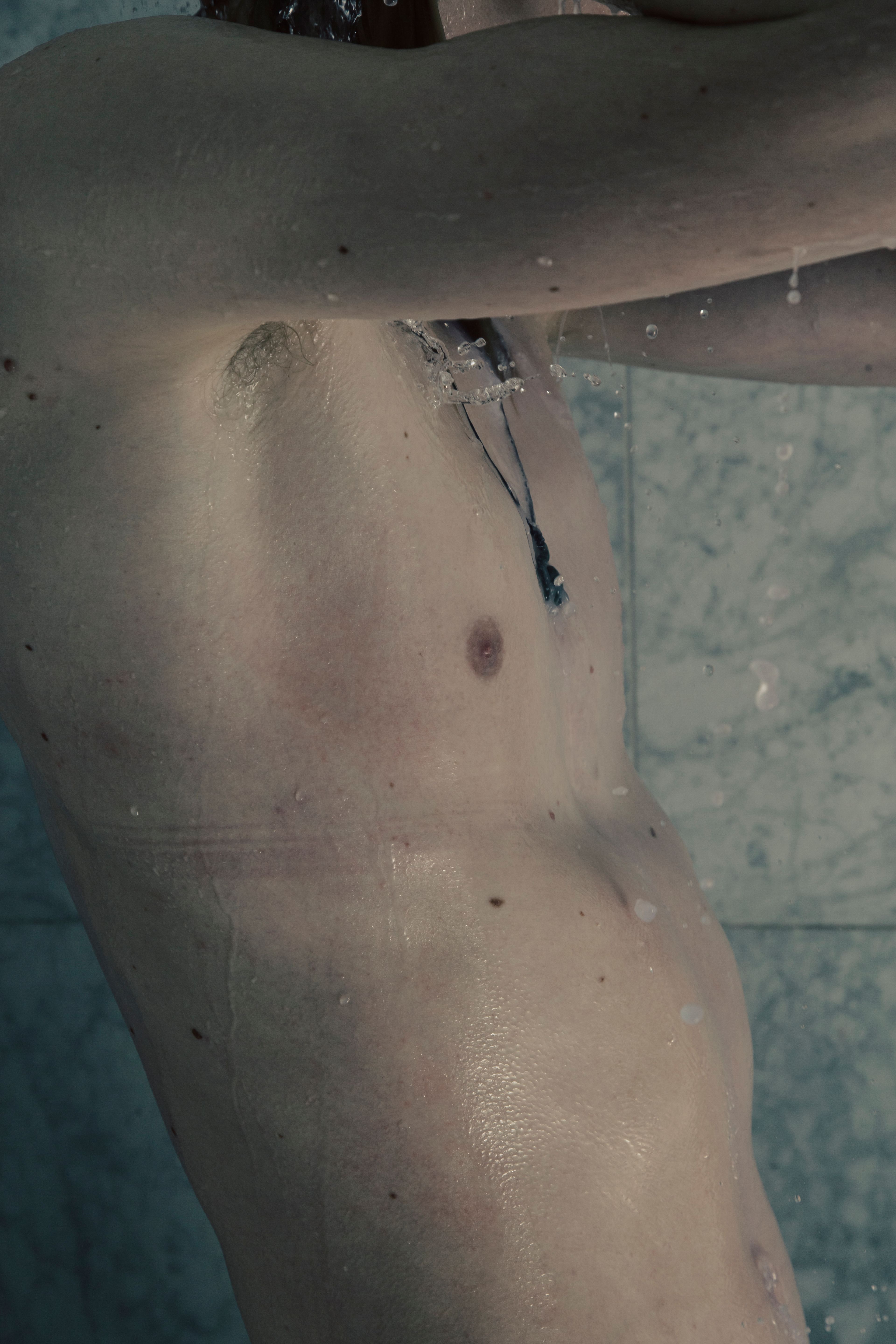 Senna Bodile: Torso van een man onder de douche, met waterdruppels. Portret door Joep van Drunen Photography.