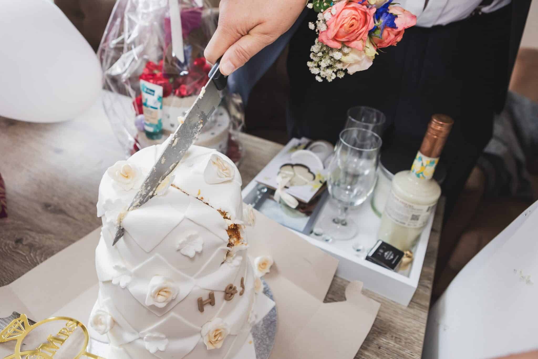 Het aansnijden van de bruidstaart met corsage in beeld