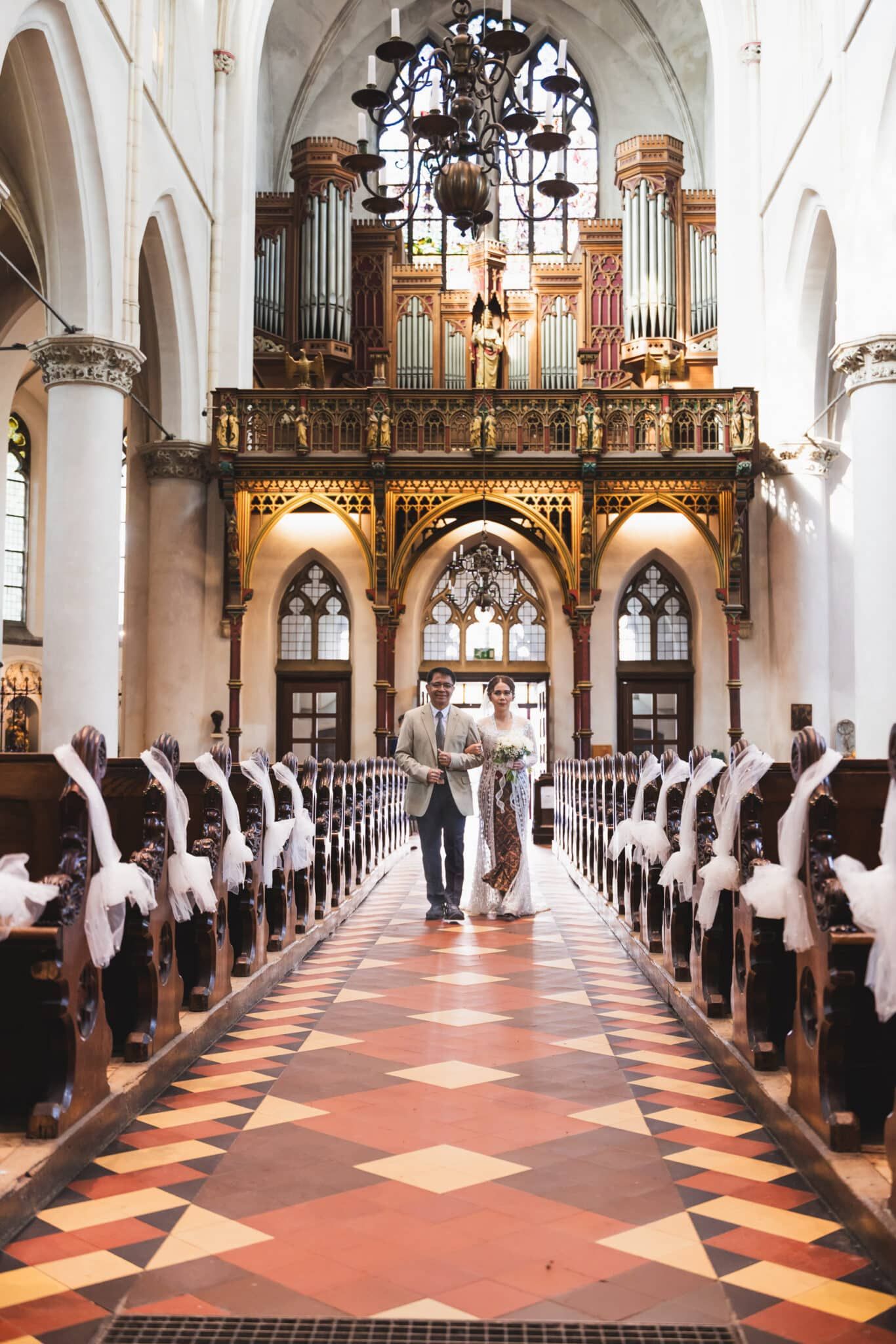 Trouwfotografie: bruidspaar loopt door het gangpad in de kerk