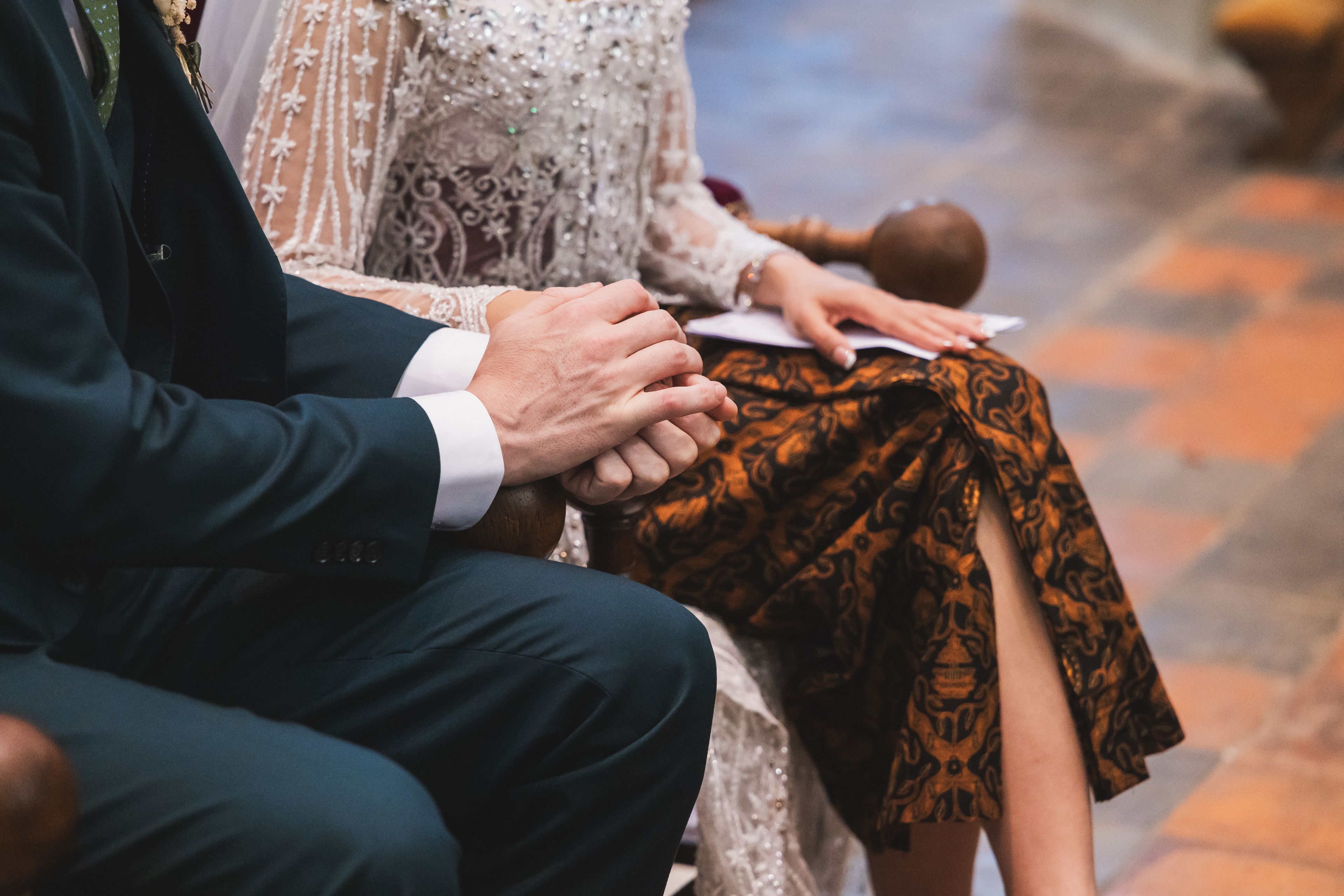 Trouwfotografie: Bruidspaar houdt elkaars handen vast tijdens de ceremonie. Detailopname van de trouw. Joep van Drunen Photography