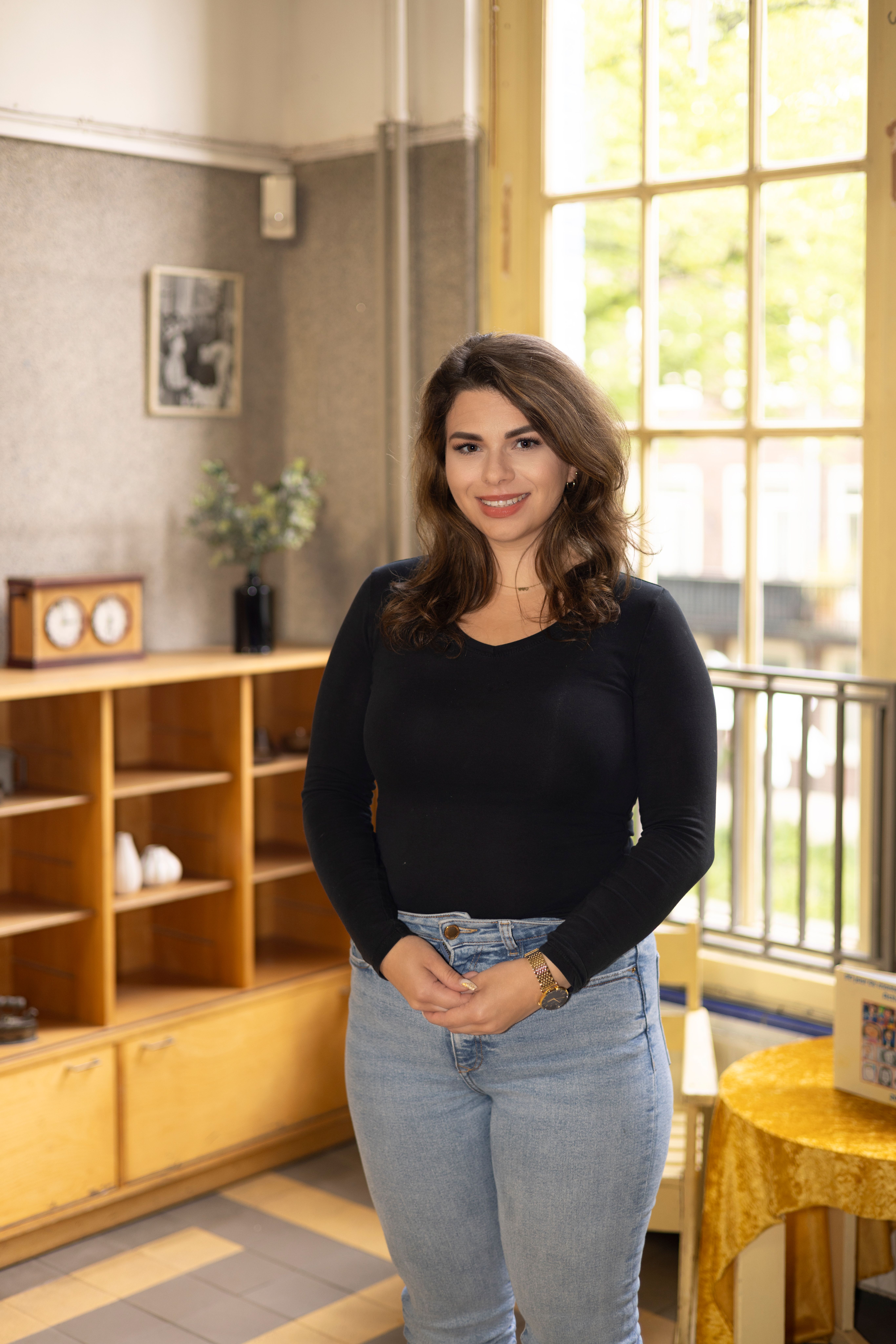 Portretfotografie van Kim, een lachende vrouw met bruin haar in een zwarte top en jeans. Kim portret. Joep van Drunen Photography