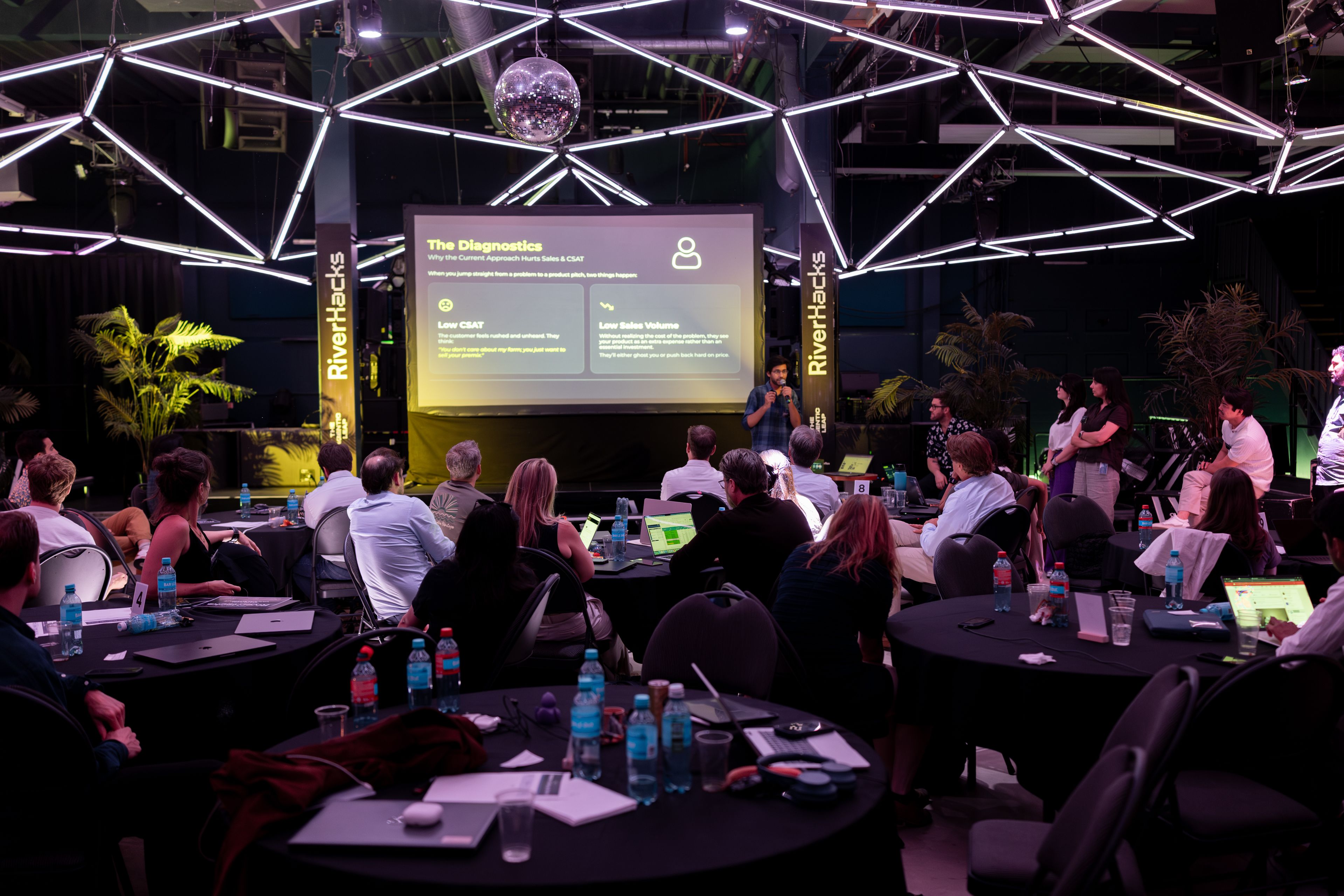 Eventfotografie RiverHacks: publiek volgt de presentatie onder het lichtframe