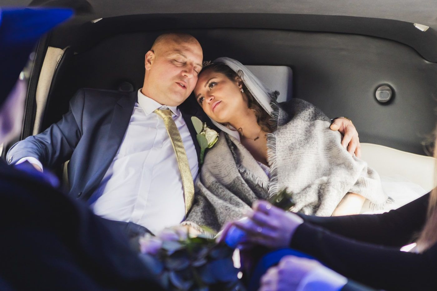 Bruidspaar samen op de achterbank van de trouwauto