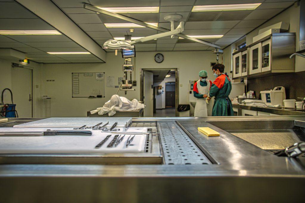 Autonoom documentaire foto: Autopsie kamer met instrumenten en medisch personeel. Onderzoekstafel in sectiekamer. Joep van Drunen Photography