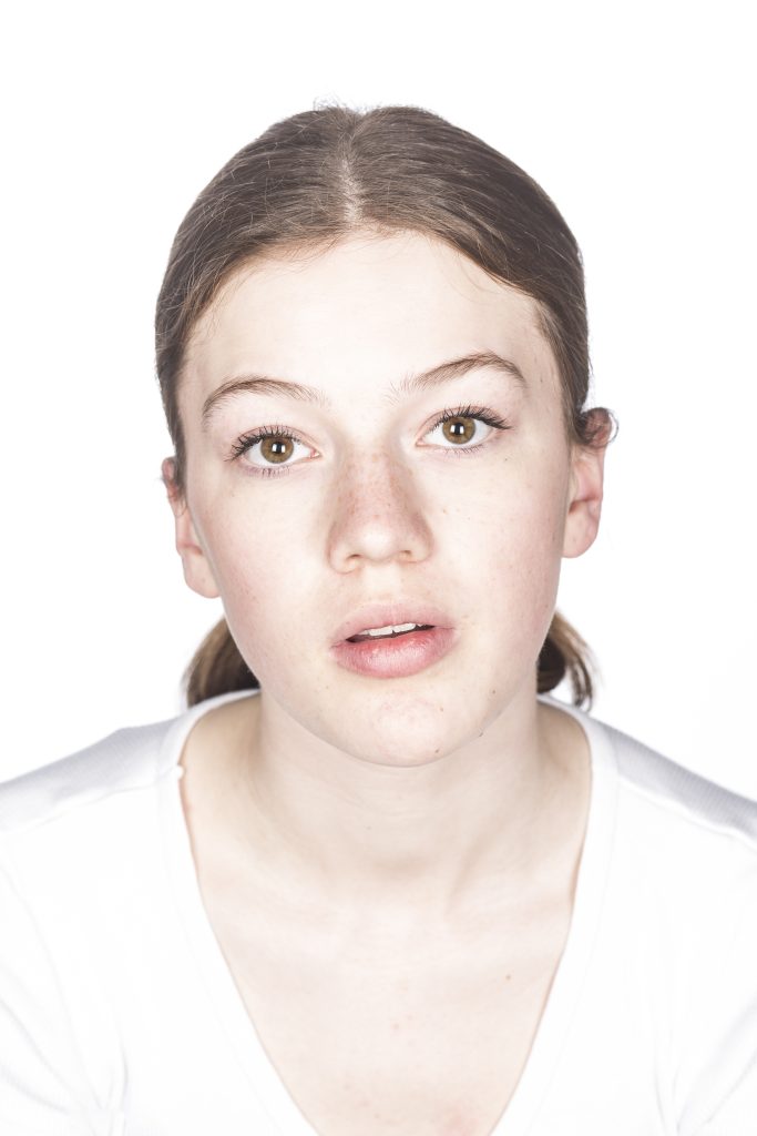 Portretfotografie van een jonge vrouw met bruin haar en sproeten, witte achtergrond. Joep van Drunen Photography