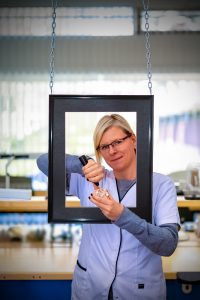 Portretfotografie Denise: Vrouw werkt aan gebitsprothese, gefotografeerd door een hangend fotolijst. Joep van Drunen Photography