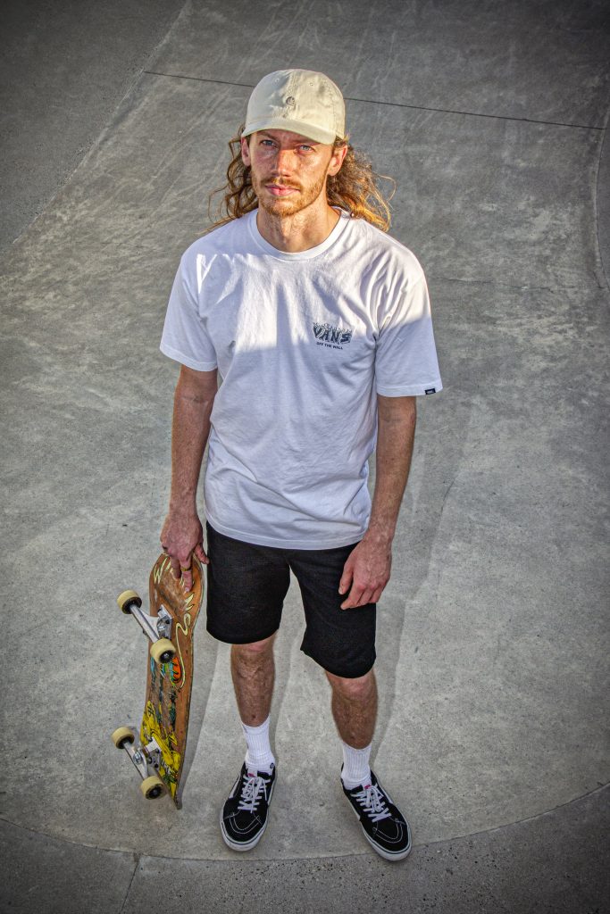 Portretfotografie: Man met skateboard in skatepark, witte Vans T-shirt en pet. Foto Joep van Drunen Photography.