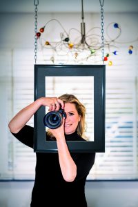 Portretfotografie van Sacha met camera in lijst. Vrouwelijk portret met spiegelreflexcamera. Joep van Drunen Photography