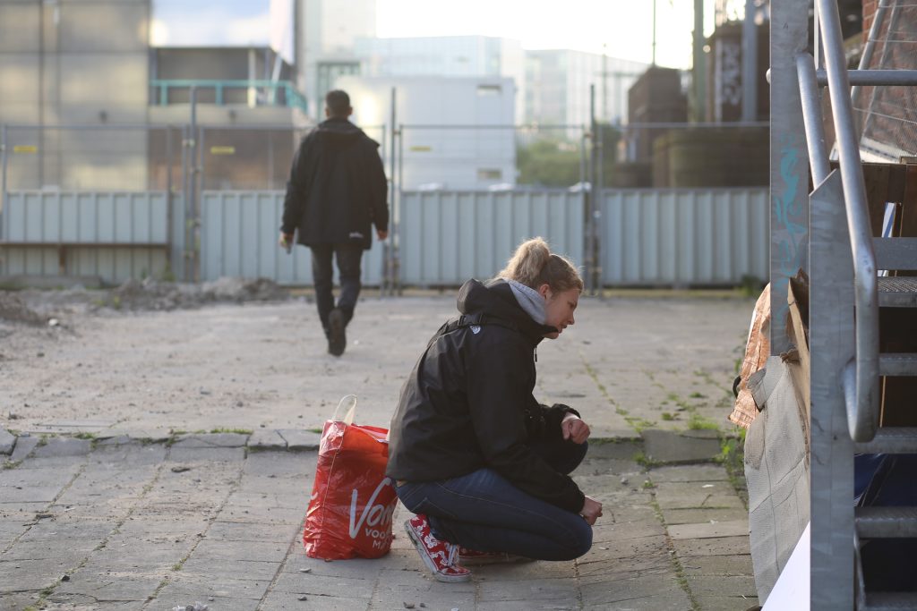 Veldwerk foto: Vrouw hurkt buiten, man loopt weg. Joep van Drunen Photography