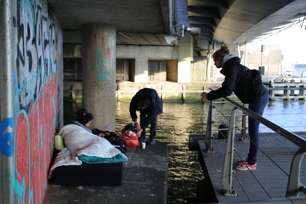 Veldwerk foto: Dakloze onder brug krijgt hulp van vrijwilligers. Armoede reportage, Joep van Drunen Photography.
