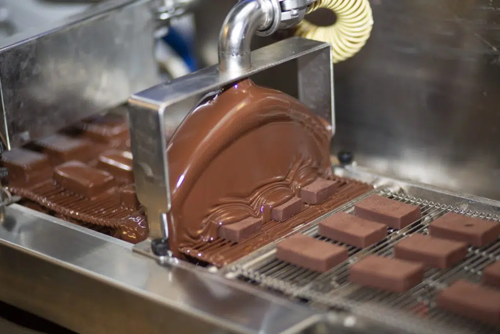 Eventfotografie: Chocoladefabriek met machine die chocoladerepen maakt, gieten van chocolade. Joep van Drunen Photography