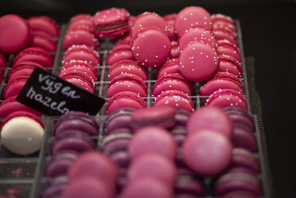 Eventfotografie: Roze en paarse macarons op een rij, met een bordje 'vijgen hazelnoot'. Joep van Drunen Photography