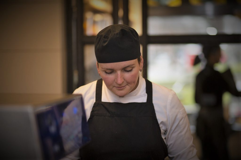 Eventfotografie: Kok in zwarte schort en muts aan het werk. Sfeerbeeld. Joep van Drunen Photography