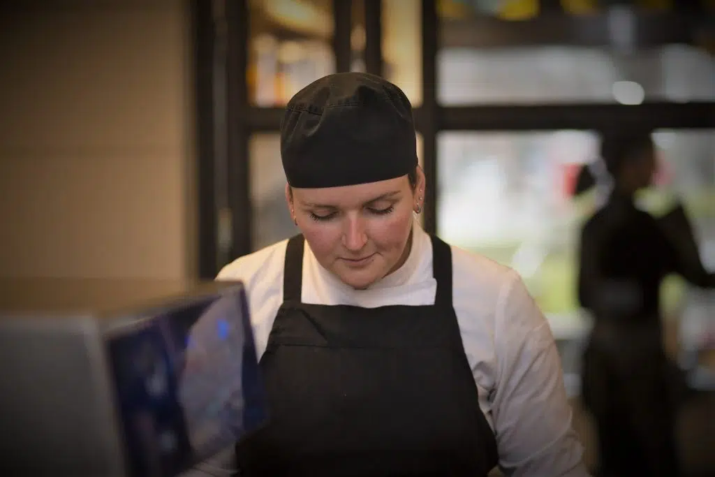 Eventfotografie: Kok in zwarte schort en muts aan het werk. Sfeerbeeld. Joep van Drunen Photography