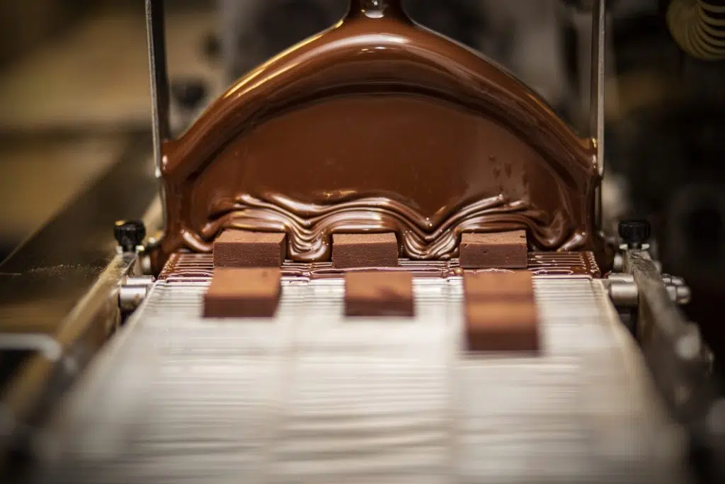 Eventfotografie: Chocolade productie op een lopende band, chocolade wordt gegoten. Joep van Drunen Photography