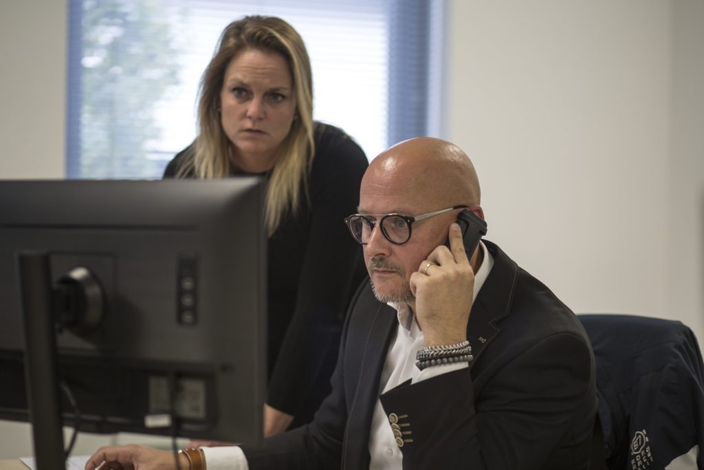 Zakelijk portret: Man belt, vrouw kijkt naar scherm. Kantooromgeving, serieuze blik. Zakelijk, professioneel. Joep van Drunen Photography