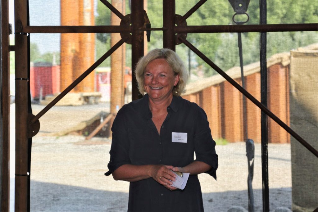 Portret van een lachende vrouw op een evenement, gefotografeerd in juni 2023. Buitenlocatie met industriële achtergrond. Joep van Drunen Photography