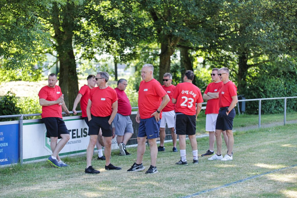 Groep mannen in rode shirts tijdens sportdag, Joep van Drunen Photography