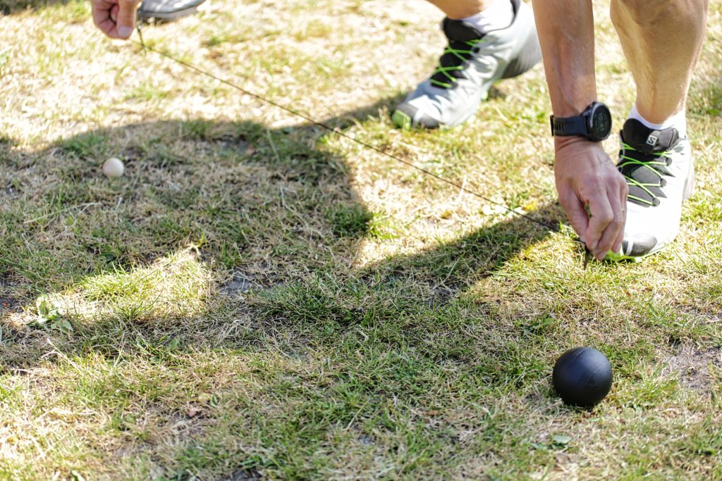 Precisiefoto van een wedstrijd met een meetlint, zwarte en witte bal op gras. Joep van Drunen Photography