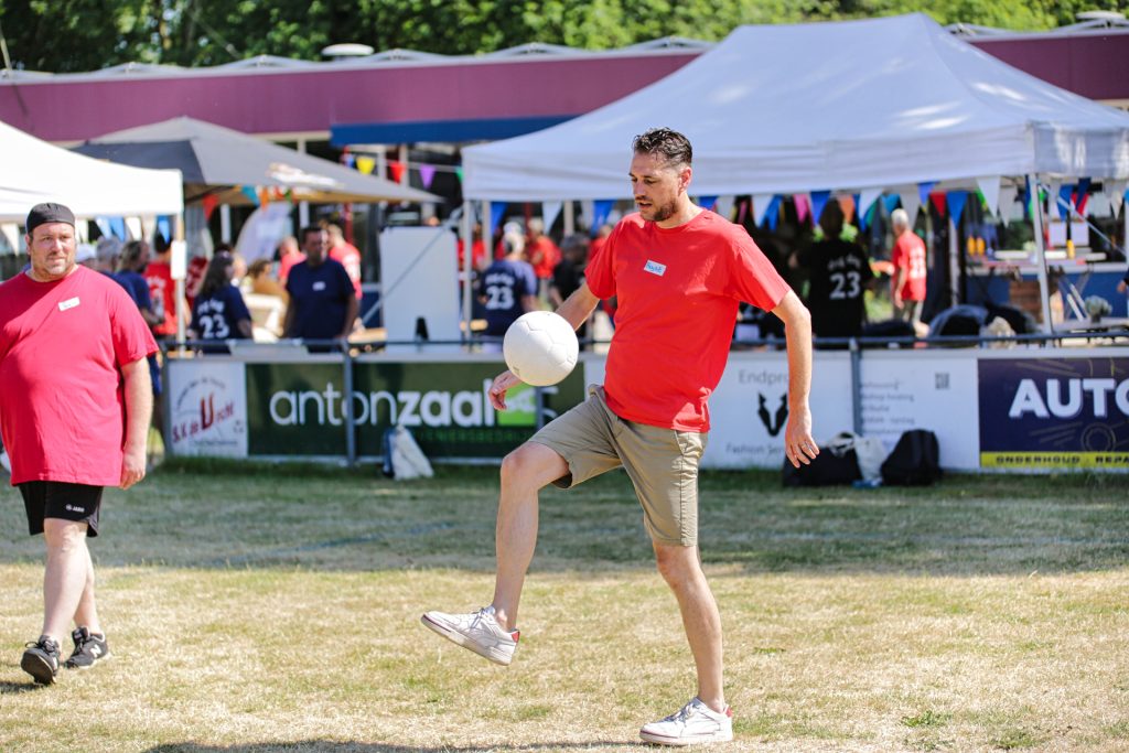 Man jongleert met bal op evenement. Zomerse sfeer met tenten en publiek op de achtergrond. Joep van Drunen Photography