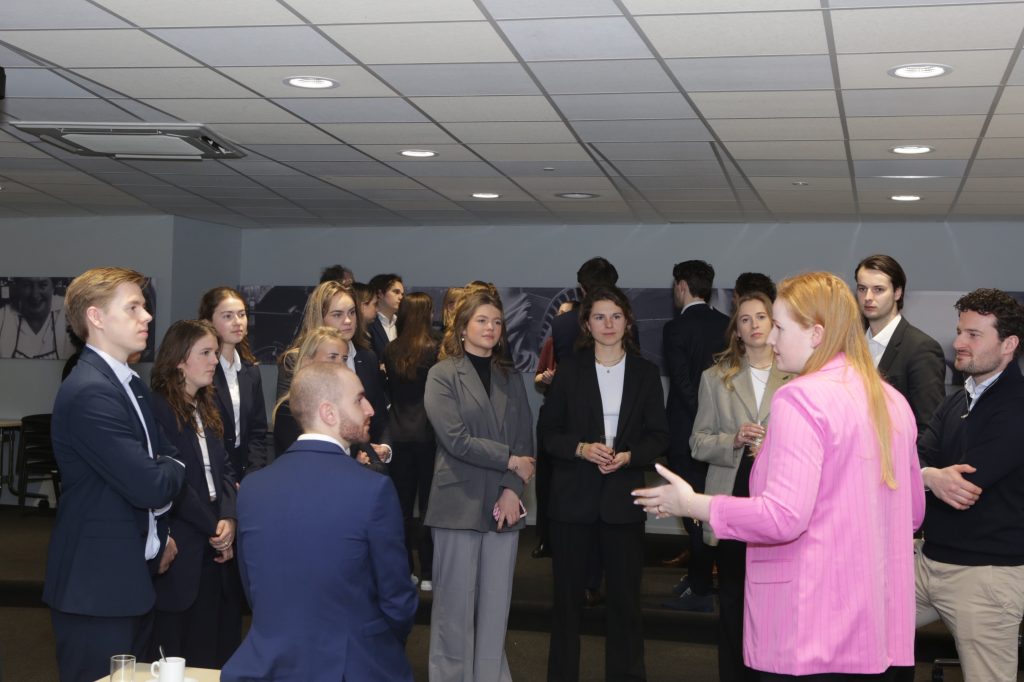 Eventfotografie IS5A5059: Groep jongvolwassenen in formele kleding luistert naar spreker tijdens een evenement. Joep van Drunen Photography