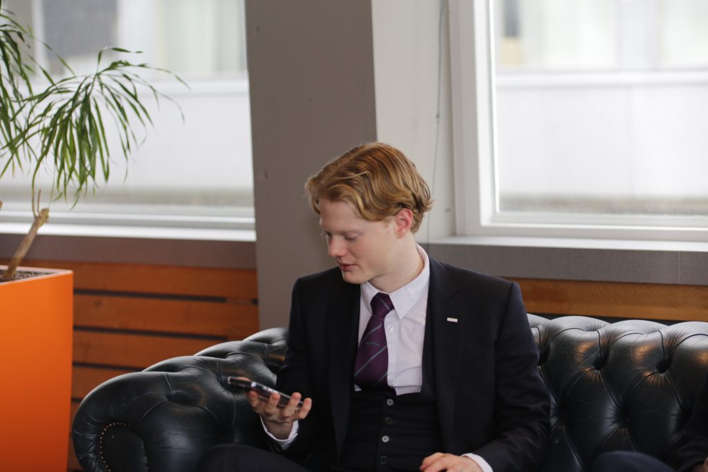 Eventfotografie: Man in pak kijkt op telefoon tijdens evenement. IS5A5124 zakelijke fotografie. Joep van Drunen Photography