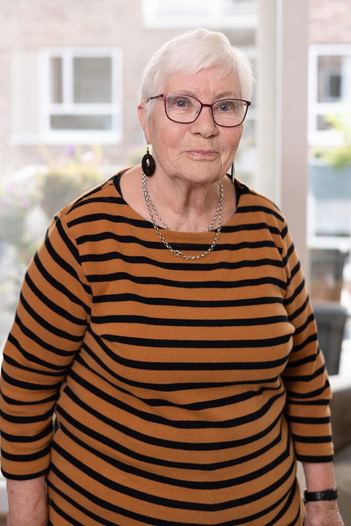 Portretfotografie van een oudere vrouw met bril en gestreepte trui. Professionele fotoshoot. Joep van Drunen Photography