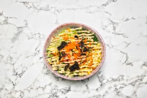 Productfotografie van een kleurrijke poké bowl met avocado, zeewier en mais op een marmeren achtergrond. Joep van Drunen Photography