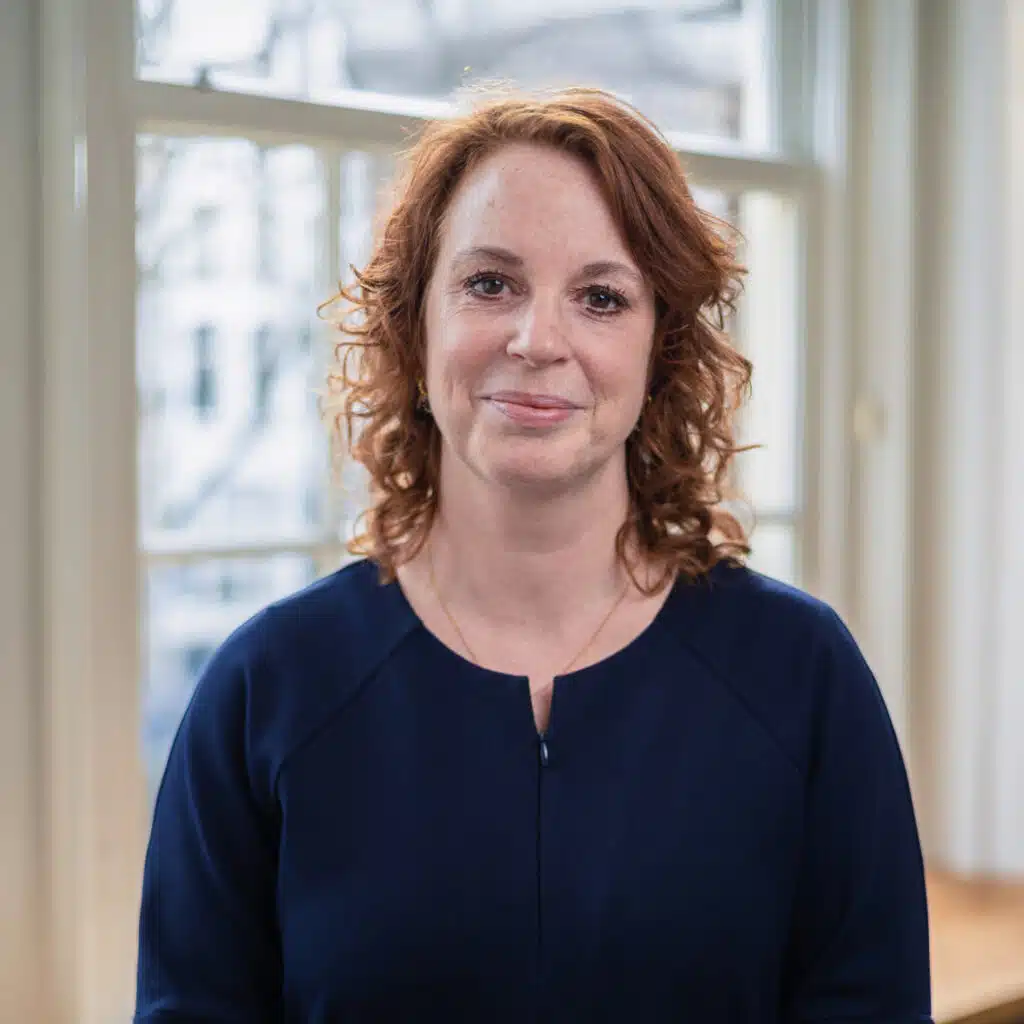 Zakelijk portret van een vrouw met rood haar voor een raam. Bedrijfsportretten Joep van Drunen Photography.