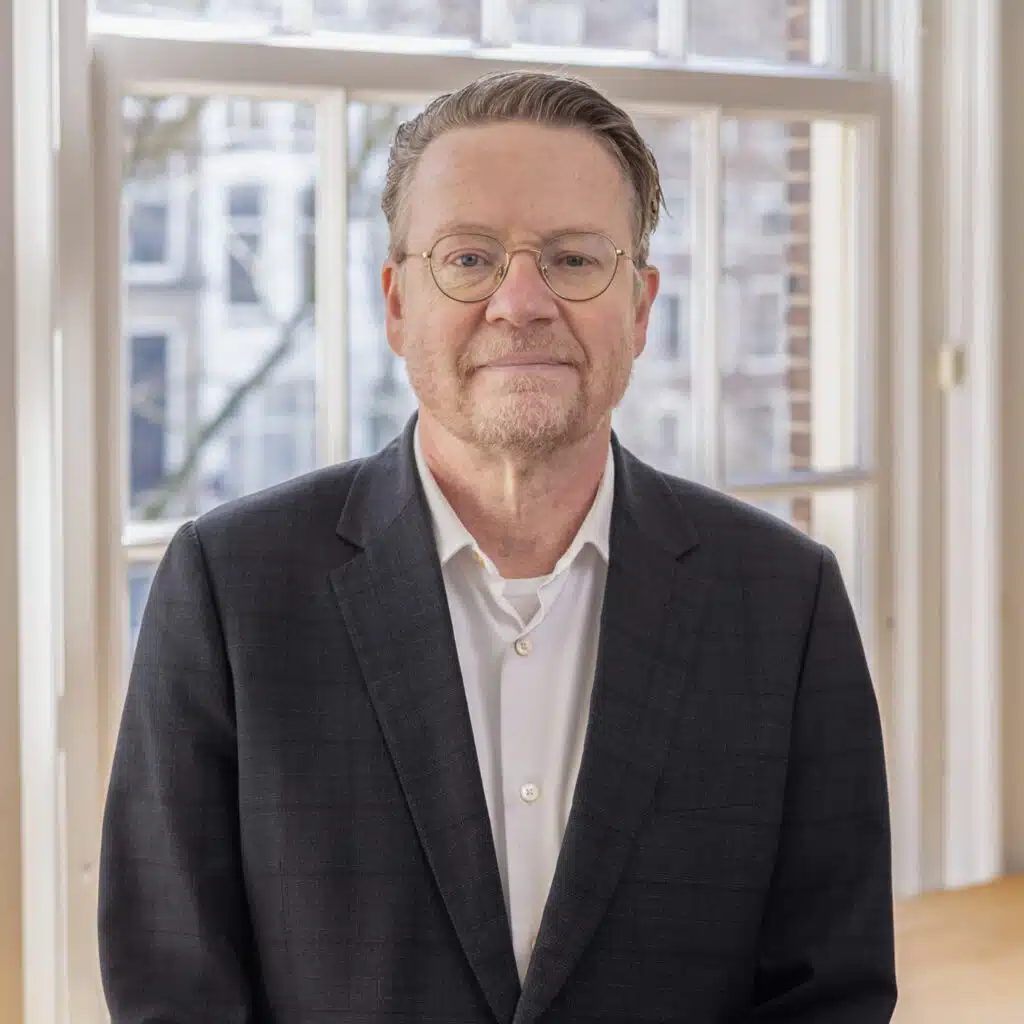 Bedrijfsportret van man met bril en pak voor raam. Zakelijk portret. Joep van Drunen Photography