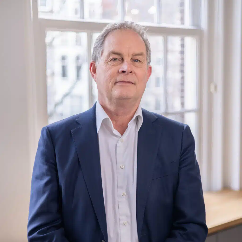 Bedrijfsportret van man in blauw pak voor raam. Professionele foto voor bedrijven. Joep van Drunen Photography