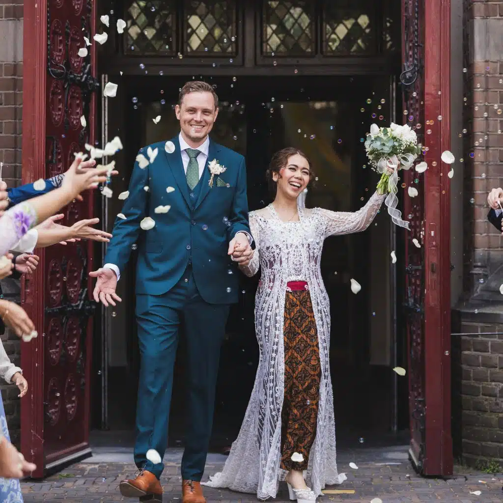 Trouwfotografie: Bruidspaar verlaat kerk, omringd door gasten en confetti. Joep van Drunen Photography.
