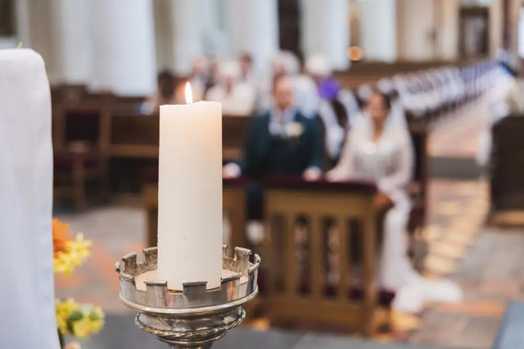 Trouwfotografie: Brandende kaars tijdens een huwelijksceremonie in een kerk. Joep van Drunen Photography