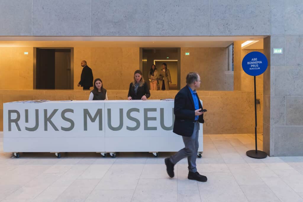 Rijksmuseum receptie bij de Abe Bonnema Prijs uitreiking. Man loopt langs balie. JVD_8634.jpg Joep van Drunen Photography