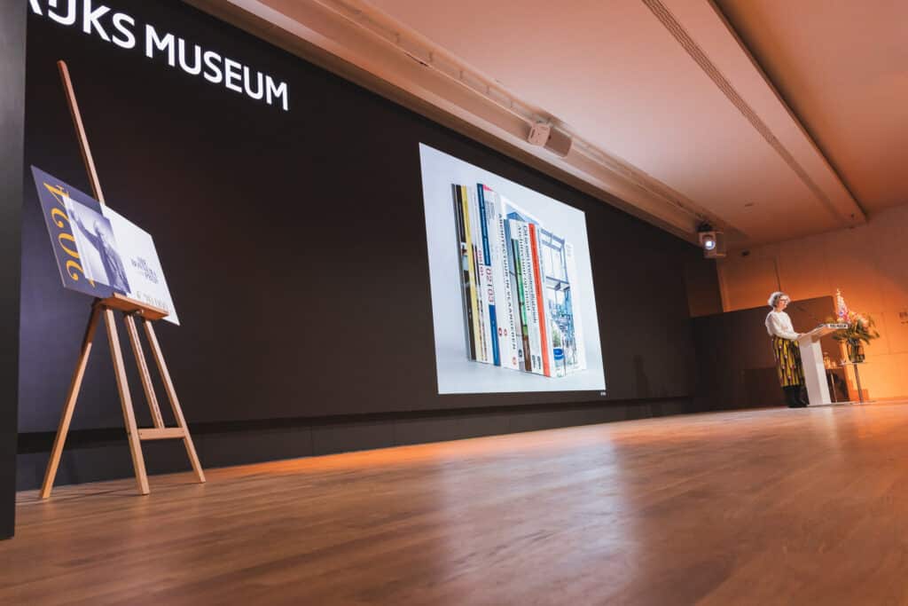 Abe Bonnema Prijs uitreiking, presentatie met boeken en spreker op podium. JVD_8872, Joep van Drunen Photography