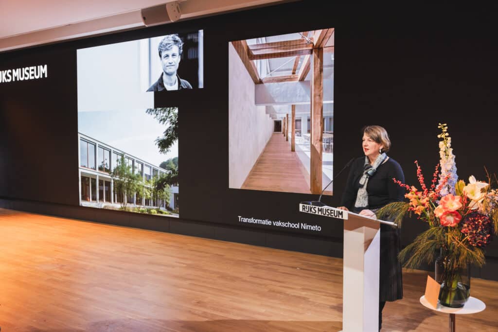 Uitreiking Abe Bonnema Prijs. Spreker op podium met foto's van architectuurprojecten. JVD_9135 Joep van Drunen Photography