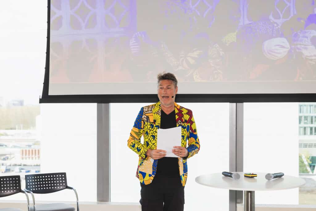 Eventfotografie Albert Schweitzer Prijs: Spreker in kleurrijk jasje presenteert tijdens evenement. Joep van Drunen Photography