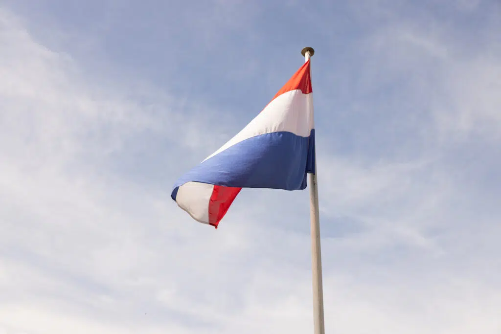 Nederlandse vlag wappert in de wind tegen een blauwe lucht, ter herdenking van Nusantara. Joep van Drunen Photography