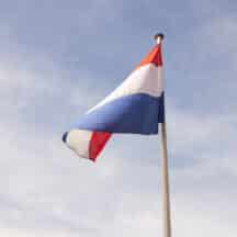 Nederlandse vlag wappert in de wind tegen een blauwe lucht, ter herdenking van Nusantara. Joep van Drunen Photography