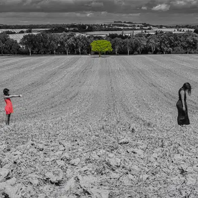 Documentaire en autonome foto: Vrouw in rode jurk en vrouw in zwart op akker met groene boom, Joep van Drunen Photography Amsterdam